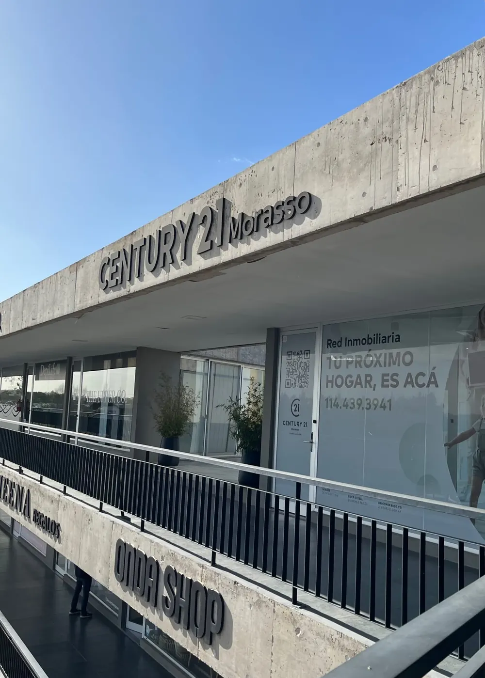 La oficina de Century 21 Morasso en Ven Street Center: el cartel sobre el hormigón y la vidriera que dice Tu próximo hogar, es acá